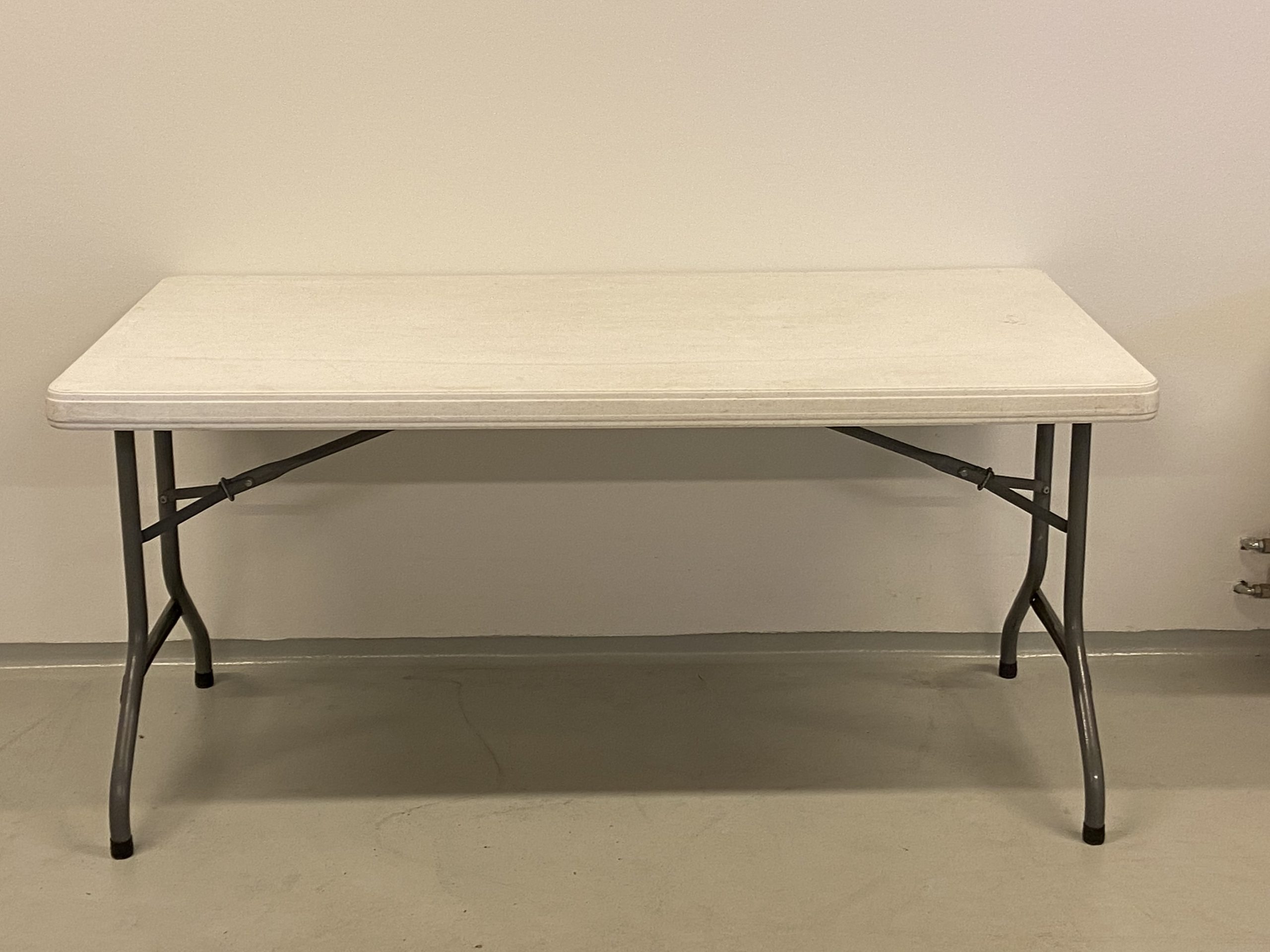 På billedet er et fint aflangt bord med hvid plastikplade og stålben.